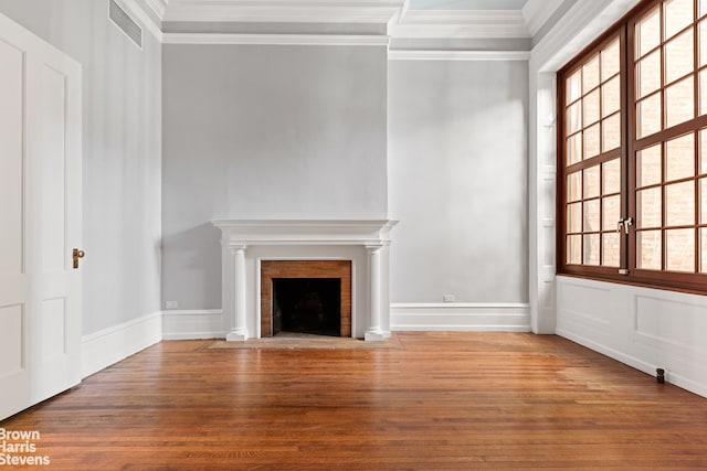 unfurnished living room featuring a fireplace with flush hearth, visible vents, crown molding, and wood finished floors