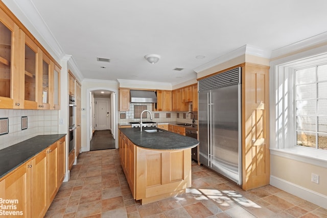 kitchen with crown molding, stainless steel appliances, arched walkways, a sink, and light brown cabinetry