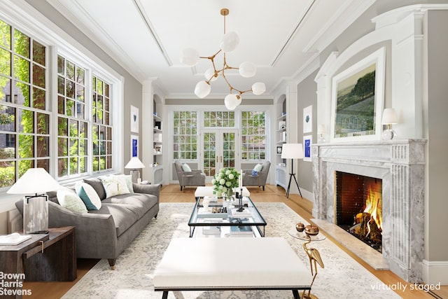 living area with a wealth of natural light, built in shelves, a chandelier, and crown molding