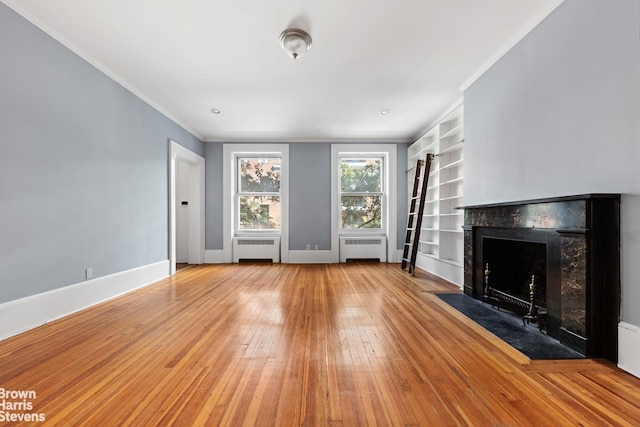 unfurnished living room with baseboards, radiator heating unit, ornamental molding, and wood-type flooring