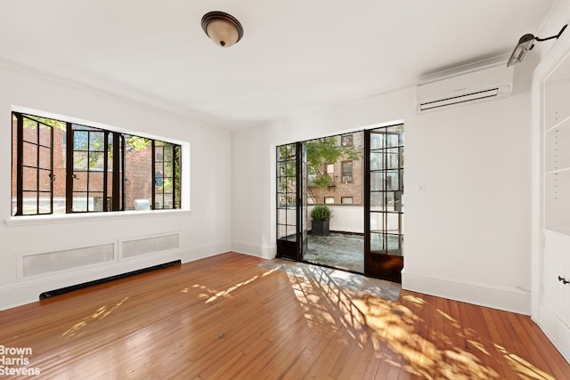 foyer entrance featuring a wall unit AC, plenty of natural light, baseboards, and wood-type flooring