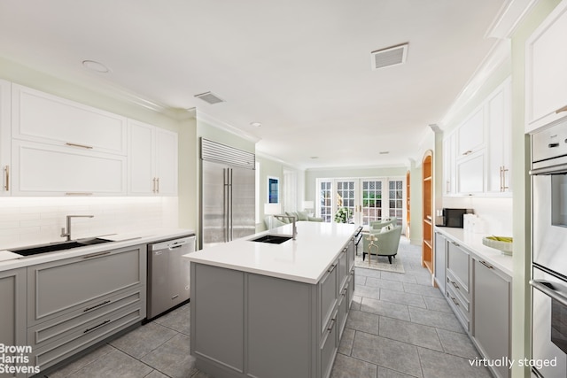 kitchen with stainless steel appliances, light countertops, visible vents, a kitchen island, and a sink