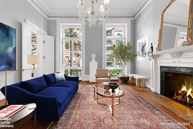 living room with crown molding, a notable chandelier, wood finished floors, and a premium fireplace