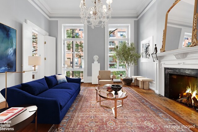 living area with a fireplace, crown molding, wood finished floors, and an inviting chandelier