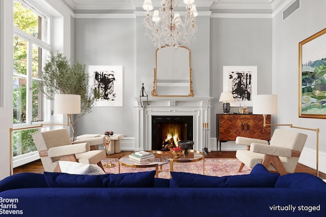 living area featuring a chandelier, visible vents, wood finished floors, and ornamental molding