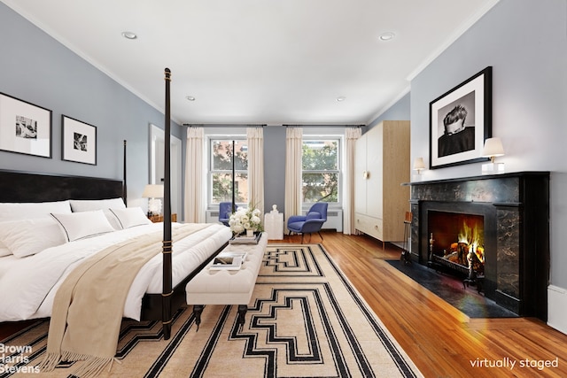 bedroom with a high end fireplace, recessed lighting, crown molding, and wood finished floors