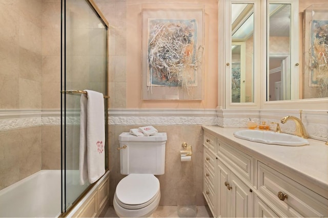 full bathroom with vanity, toilet, combined bath / shower with glass door, and tile walls