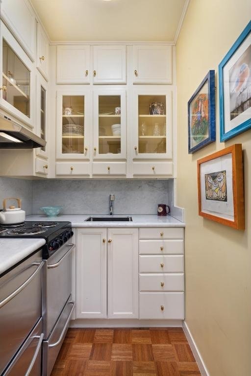 kitchen featuring sink, stainless steel range with gas cooktop, dark parquet floors, and white cabinets