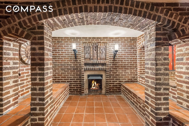 wine area with brick wall, tile patterned floors, and a fireplace