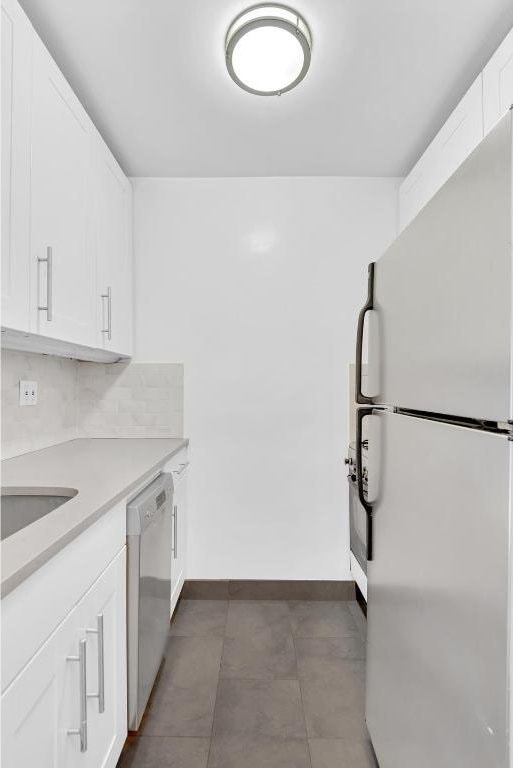 kitchen featuring sink, dishwasher, white cabinetry, decorative backsplash, and white fridge