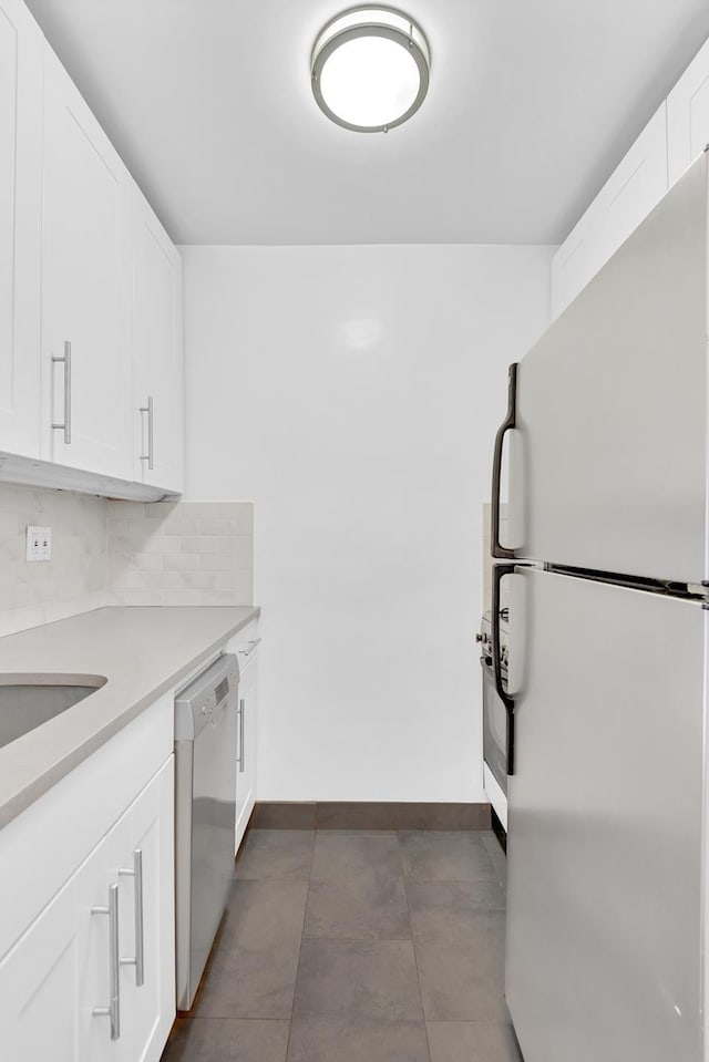 kitchen with light countertops, freestanding refrigerator, white cabinetry, tasteful backsplash, and stainless steel dishwasher