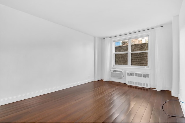 empty room with radiator heating unit, baseboards, dark wood-style flooring, and a wall mounted air conditioner