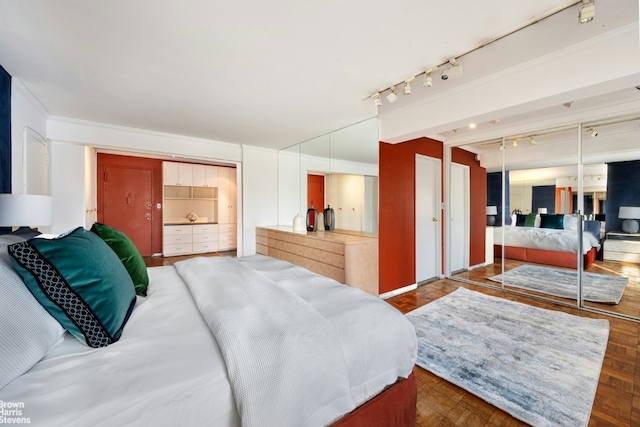 bedroom featuring a closet, rail lighting, and dark parquet floors