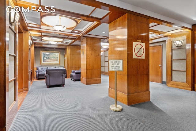 lobby with coffered ceiling, wooden walls, and beamed ceiling
