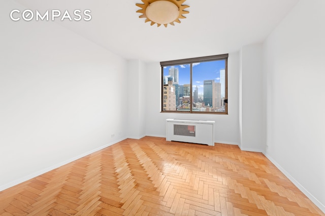 empty room featuring radiator, baseboards, and a skyline view