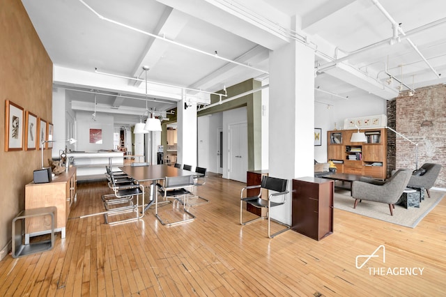 dining room featuring wood-type flooring, brick wall, and rail lighting