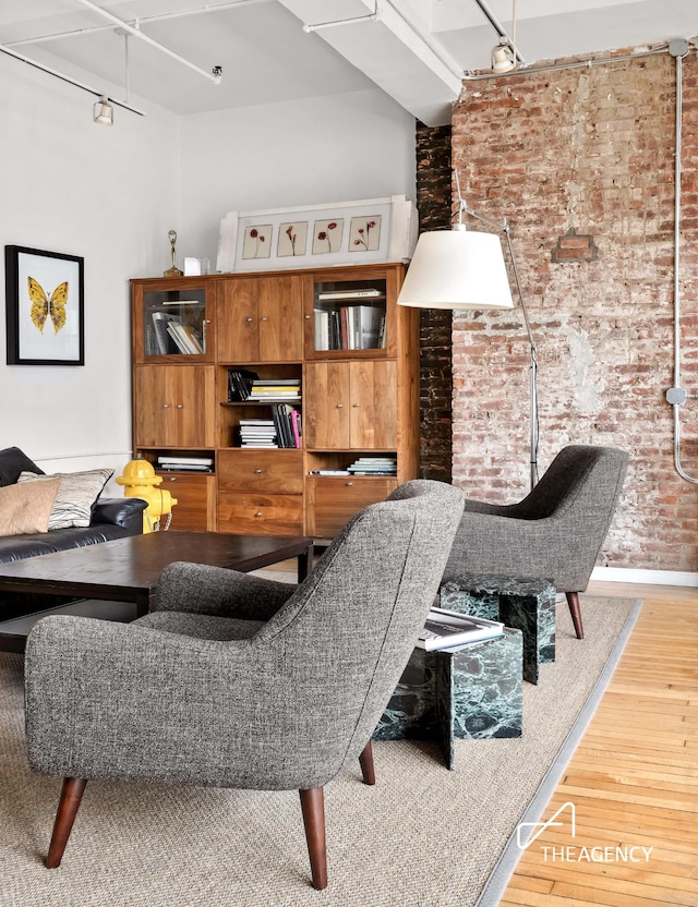 dining area with brick wall and wood finished floors