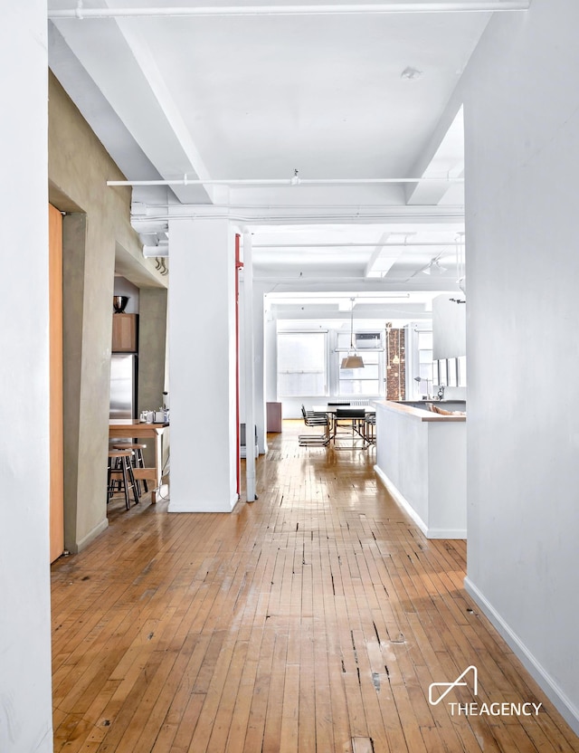 hallway featuring wood-type flooring and baseboards