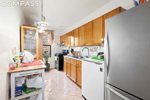 kitchen with decorative light fixtures, light tile patterned floors, appliances with stainless steel finishes, and sink