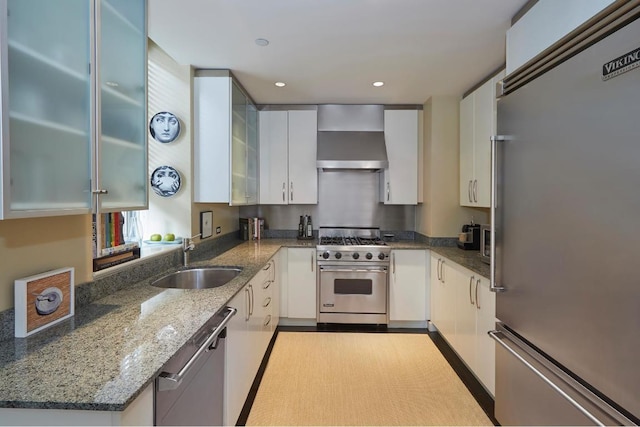 kitchen with white cabinetry, sink, high quality appliances, and wall chimney range hood