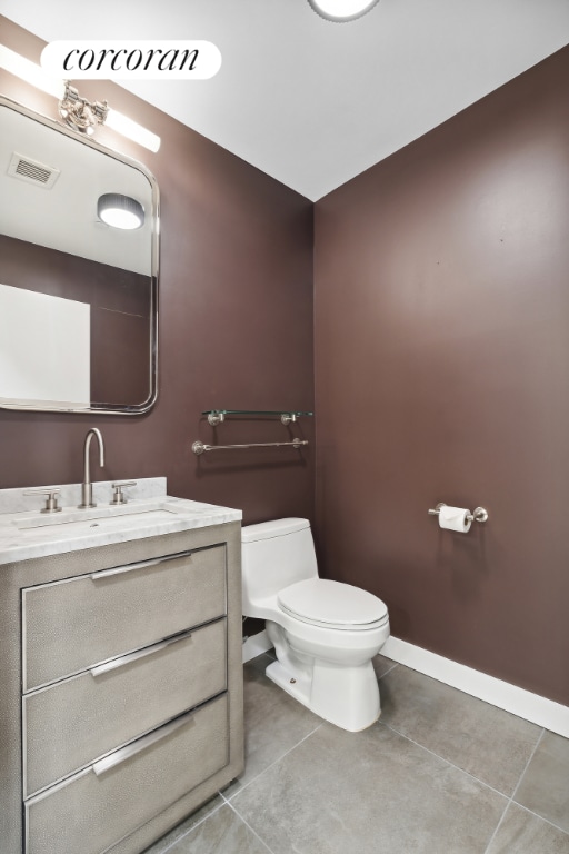 bathroom with toilet, vanity, and tile patterned flooring