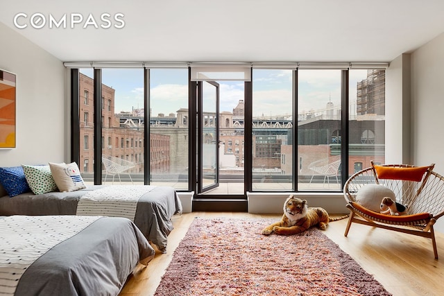 bedroom with expansive windows, wood finished floors, and a city view