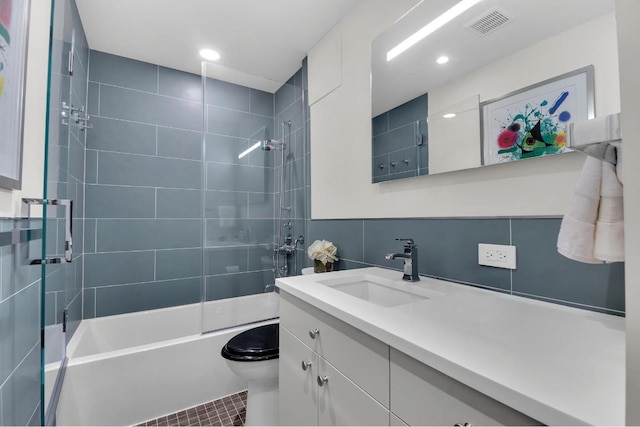 full bathroom featuring toilet, tiled shower / bath, tile walls, tile patterned floors, and vanity