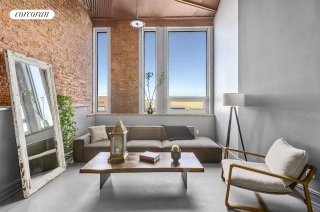 interior space with a towering ceiling, brick wall, and concrete flooring