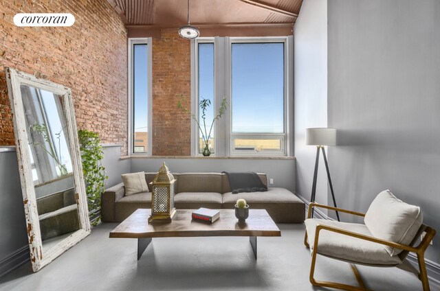 interior space with brick wall, concrete flooring, and a high ceiling