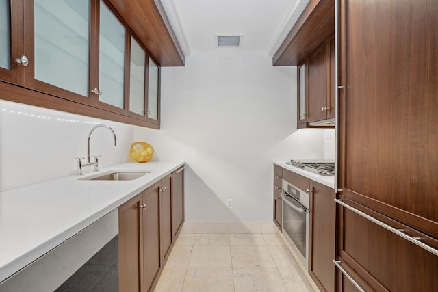 140 E 63rd St Unit 10F, New York City, NY 10065 - kitchen featuring stainless steel appliances, a sink, light countertops, and glass insert cabinets