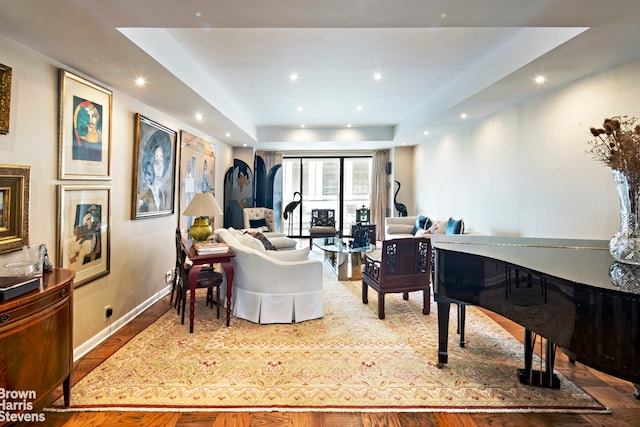 living room with baseboards, a tray ceiling, and recessed lighting