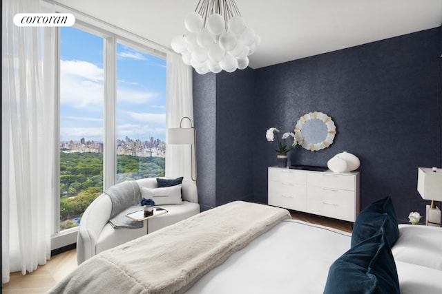 bedroom featuring expansive windows, a chandelier, and light hardwood / wood-style flooring