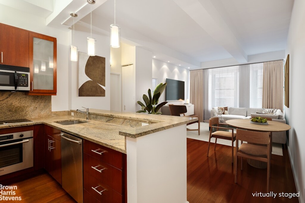 kitchen with backsplash, kitchen peninsula, sink, light stone countertops, and appliances with stainless steel finishes