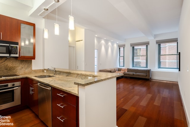 kitchen with appliances with stainless steel finishes, sink, light stone countertops, and kitchen peninsula