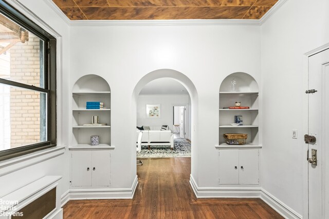 hall featuring built in shelves, crown molding, and dark wood-type flooring