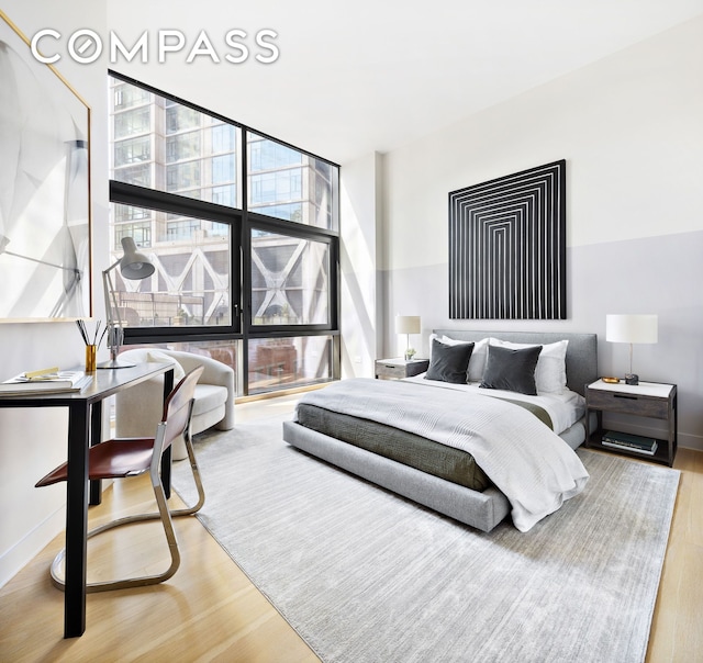 bedroom with expansive windows, baseboards, and wood finished floors