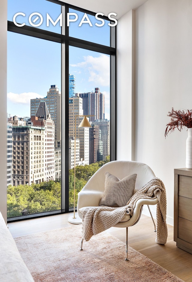 sitting room with a view of city, expansive windows, and wood finished floors