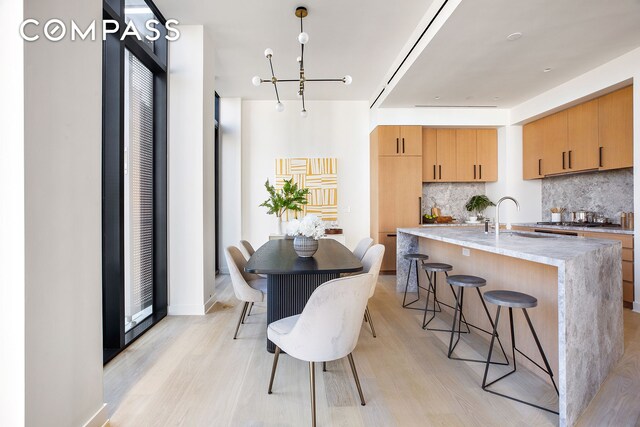 kitchen featuring light wood-style floors, a breakfast bar area, backsplash, and a sink