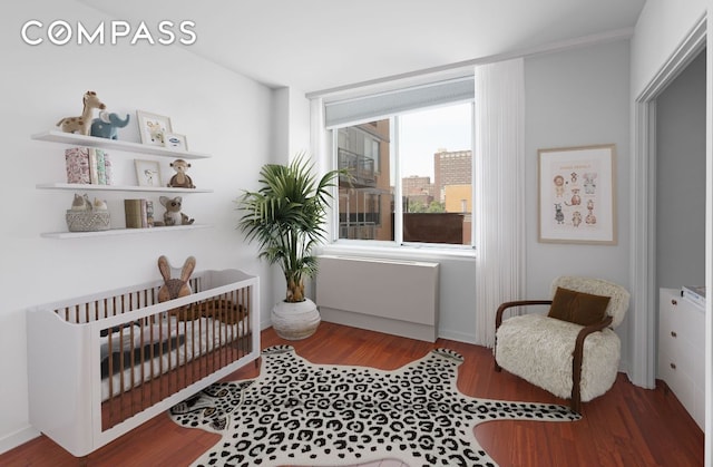 bedroom with a nursery area and wood-type flooring