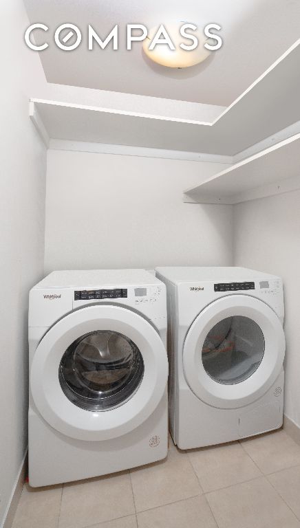 clothes washing area with washer and dryer and light tile patterned floors