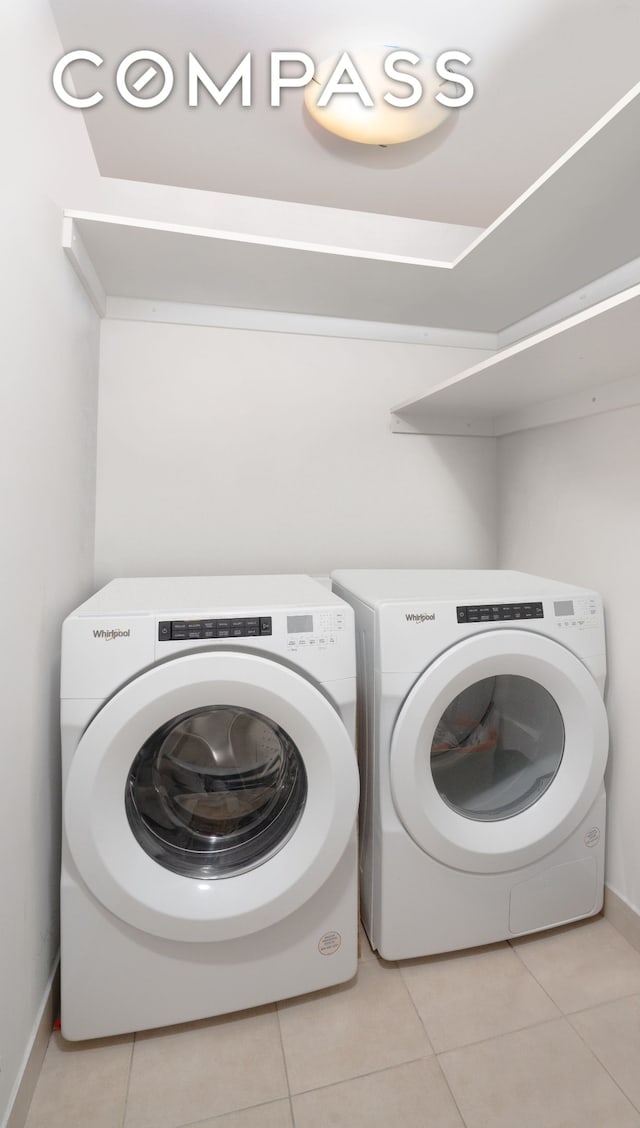 laundry area featuring baseboards, light tile patterned flooring, laundry area, and washing machine and clothes dryer