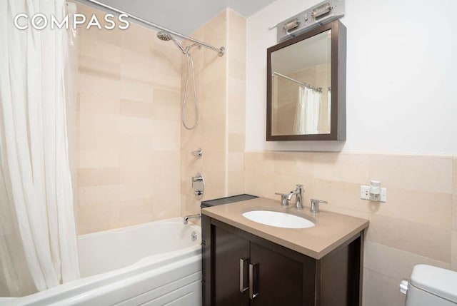 full bathroom with vanity, tile walls, shower / tub combo with curtain, and toilet