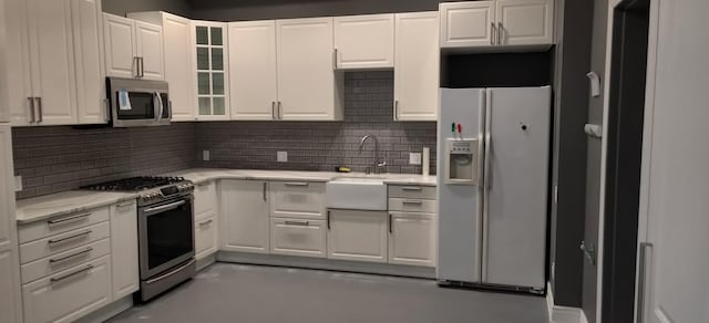 kitchen with tasteful backsplash, a sink, white cabinets, glass insert cabinets, and stainless steel appliances