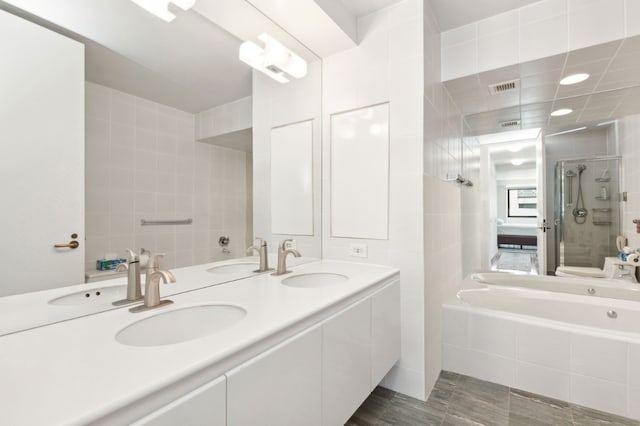 bathroom with tile walls, vanity, and separate shower and tub