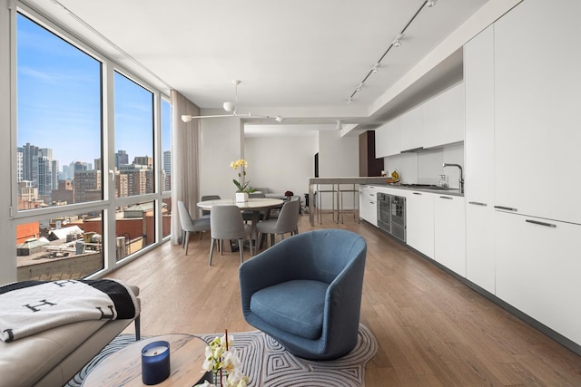 39 E 29th St Unit 25A, New York City, NY 10016 - living room with rail lighting, wood finished floors, wine cooler, a skyline view, and a wall of windows
