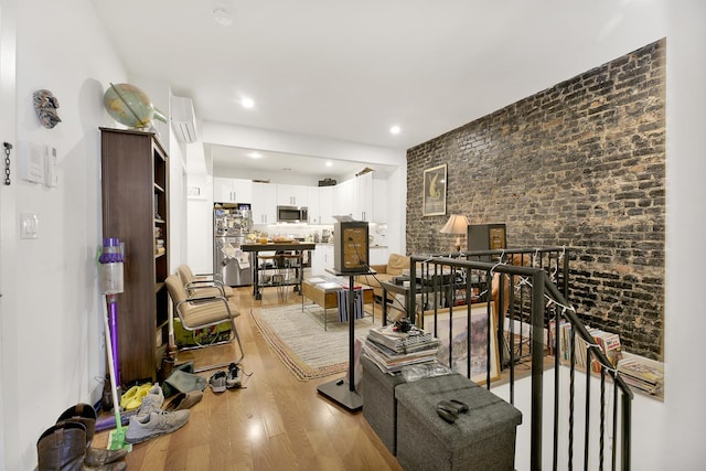 living area with recessed lighting, light wood-style floors, and brick wall