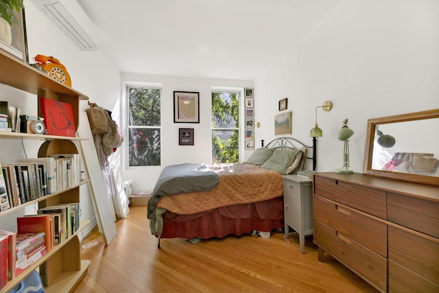 bedroom with a wall unit AC and light hardwood / wood-style floors