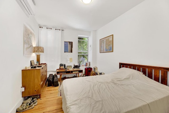 bedroom with light hardwood / wood-style flooring and an AC wall unit