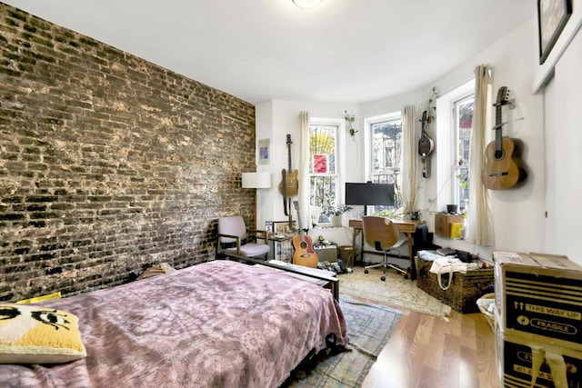 bedroom featuring hardwood / wood-style floors and brick wall