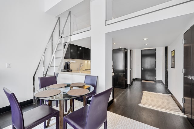 dining space featuring dark hardwood / wood-style floors, sink, and a towering ceiling